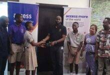Mr Olatunji (fourth) presenting a sandal to one of the students while staff of the bank and beneficiary schools look on