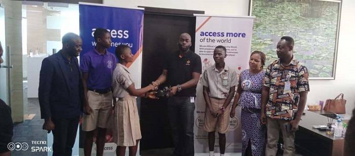 Mr Olatunji (fourth) presenting a sandal to one of the students while staff of the bank and beneficiary schools look on