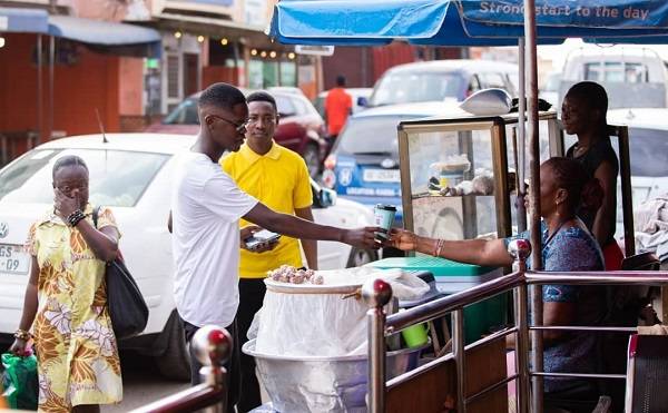 • A koko (porridge) vendor serving customers with the paper cup