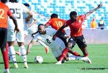 A scramble for the ball involving Jordan Ayew (in white) and Ugandan players